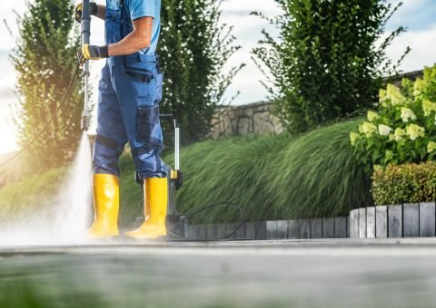 Caucasian Garden Worker Pressure Washing Residential Driveway Using Modern Pressure Washer Worker Pressure Washing Residential Driveway Using Modern Pressure Washer